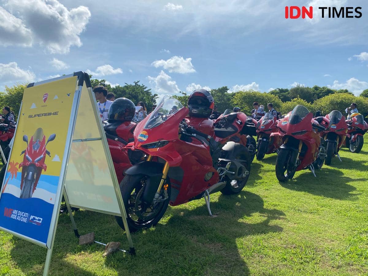 Deretan motor Ducati berwarna merah diparkir rapi di area rumput Pulau Peninsula, Nusa Dua Bali, di bawah langit cerah.