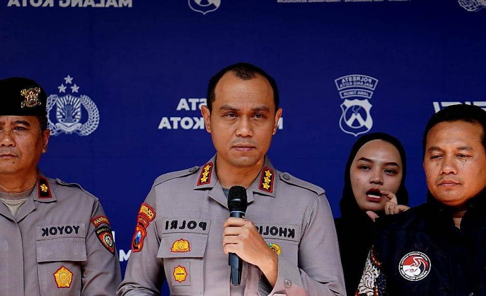 Seorang perwira polisi berpakaian dinas berbicara di depan mikrofon didampingi beberapa anggota kepolisian di Malang Kota.
