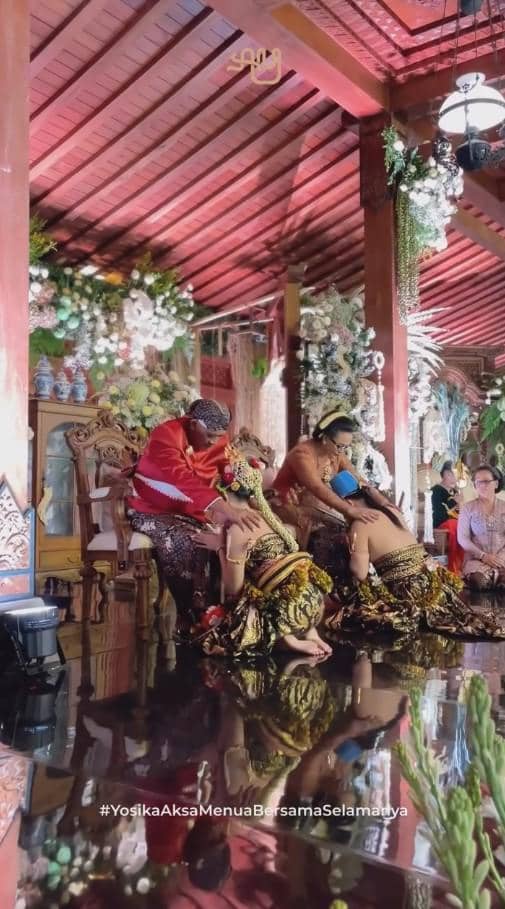 Pasangan pengantin mengenakan busana adat Jawa melakukan prosesi sungkeman kepada orang tua dalam acara ngunduh mantu di pendopo tradisional.