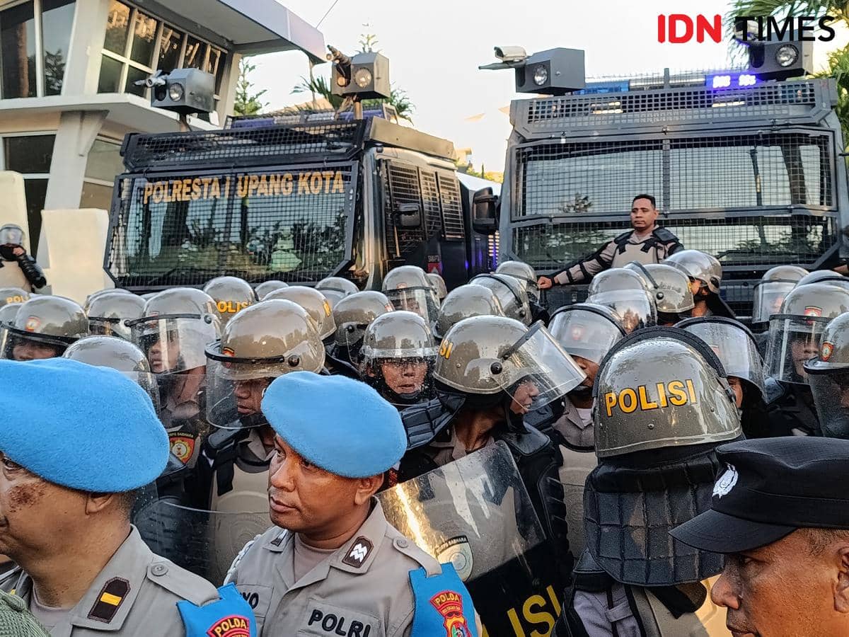 Barisan polisi dengan helm dan tameng berjaga di depan kendaraan taktis saat pengamanan demo di Kantor Gubernur NTT.