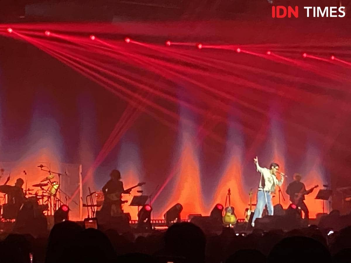 Penyanyi tampil di atas panggung konser WOODZ di The Kasablanka, Jakarta, dengan pencahayaan merah dan biru yang dramatis.