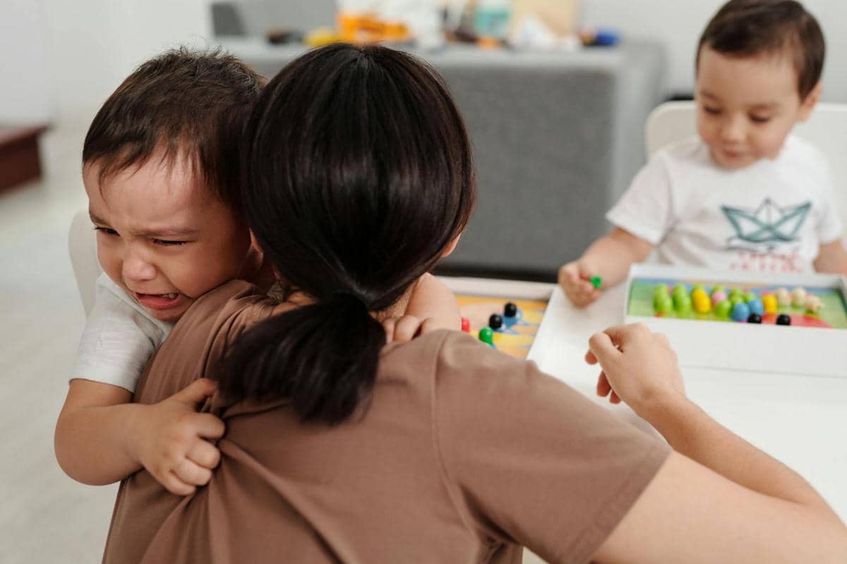 ilustrasi pengasuh menenangkan anak yang menangis di daycare 