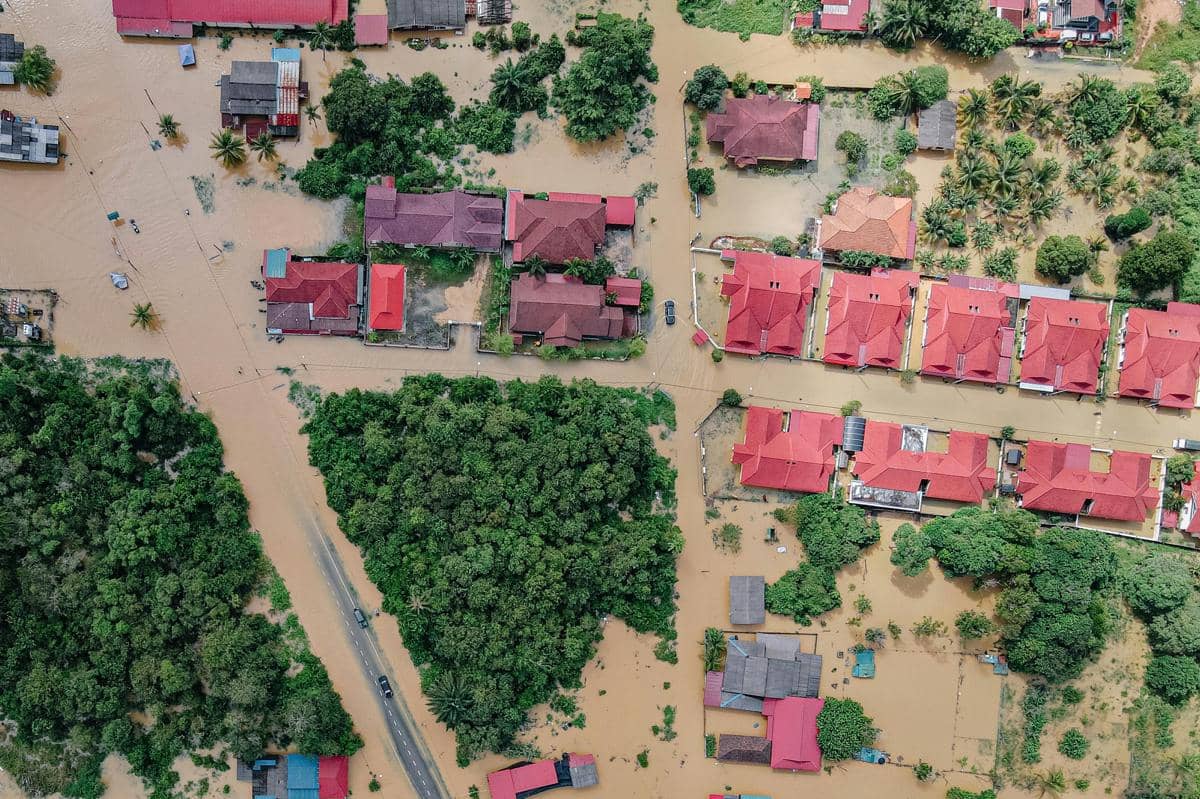Foto udara kawasan permukiman terendam banjir dengan rumah beratap merah dan air cokelat keruh
