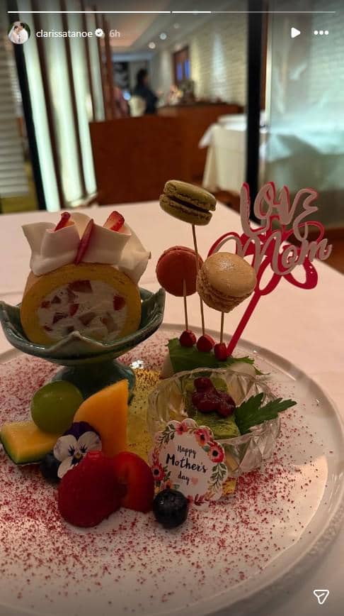 Hidangan penutup cantik dengan kue gulung buah, makaron, dan hiasan bertuliskan 'Love Mom' untuk perayaan Hari Ibu di restoran.