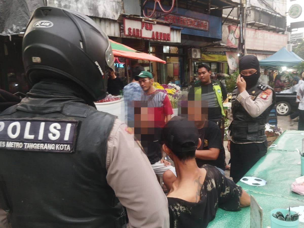 Petugas Polres Metro Tangerang Kota mengamankan beberapa orang di area Pasar Lama Tangerang dengan suasana ramai di sekitar lokasi.