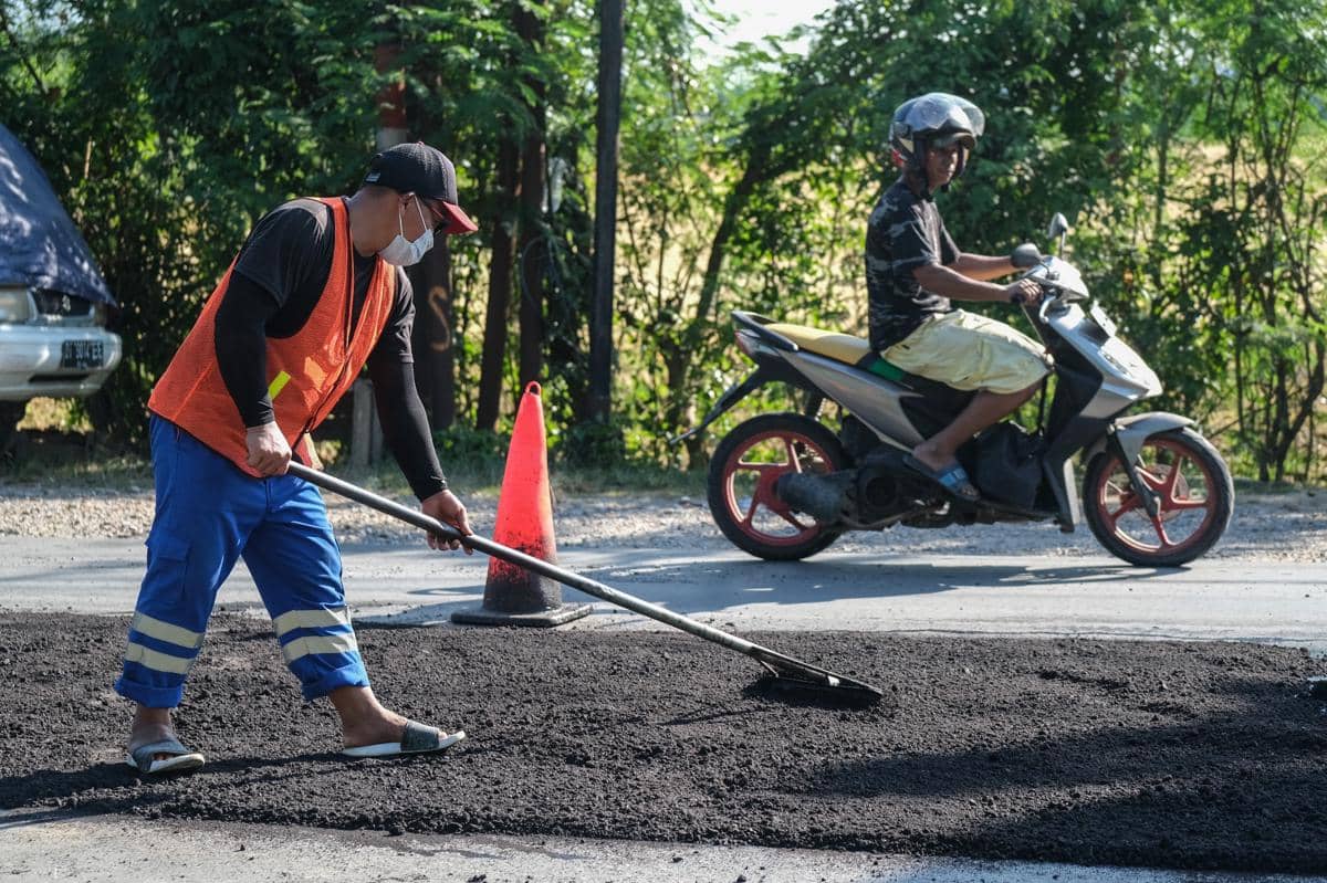 Ilustrasi seorang pekerja menyelesaikan perataan material aspal. (ANTARA FOTO/Andry Denisah)