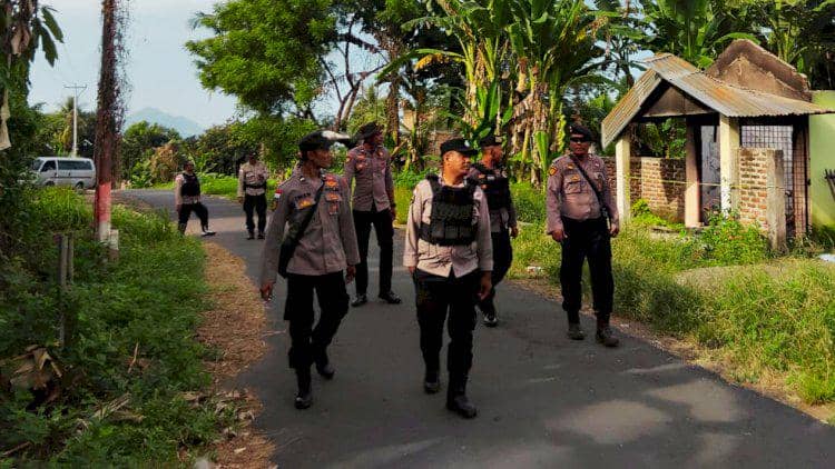 Sejumlah polisi berpakaian dinas berjalan patroli di jalan desa kawasan Flores Timur, Nusa Tenggara Timur, dikelilingi pepohonan hijau.