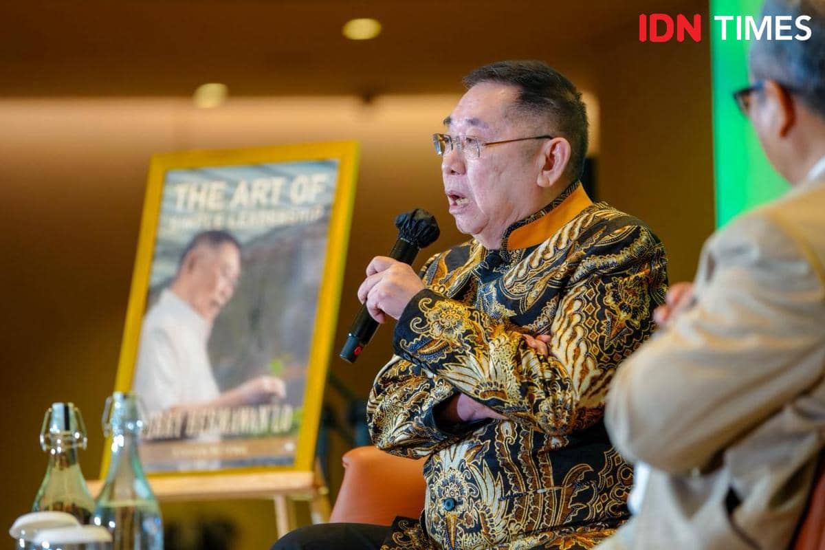 Seorang pria mengenakan batik hitam emas berbicara dengan mikrofon saat acara peluncuran buku di Tangerang.