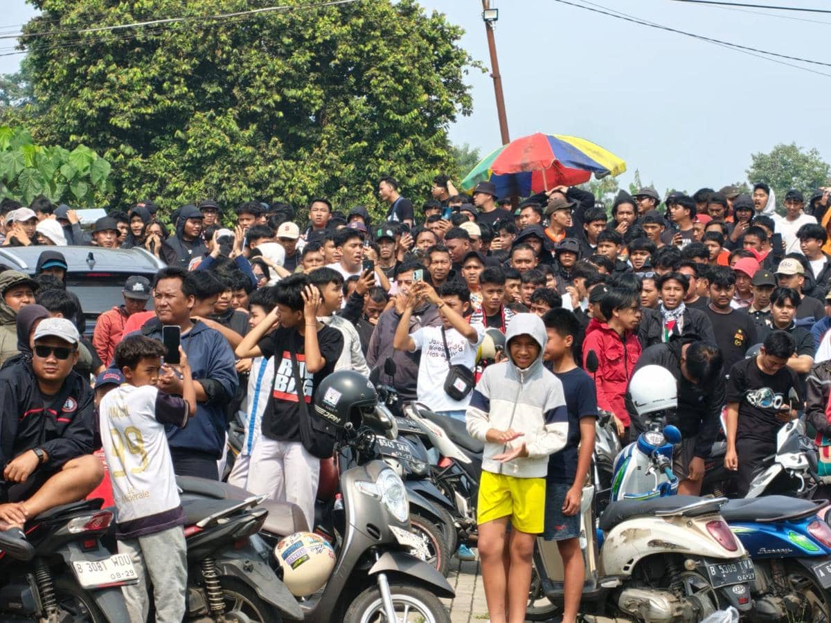 Kerumunan suporter The Jakmania mengenakan pakaian berwarna hitam dan oranye berkumpul di Sawangan untuk mendukung Persija Jakarta.