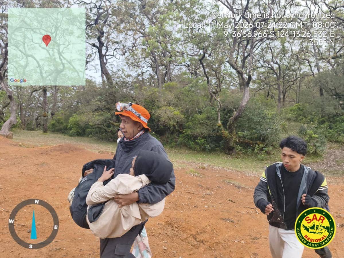 Petugas SAR membawa seorang remaja yang ditemukan setelah tersesat di kawasan hutan Gunung Mutis, dengan latar pepohonan dan tanah merah.