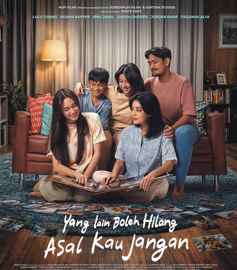 Poster film Yang Lain Boleh Hilang Asal Kau Jangan menampilkan lima orang duduk bersama di ruang keluarga dengan suasana hangat dan penuh kebersamaan.