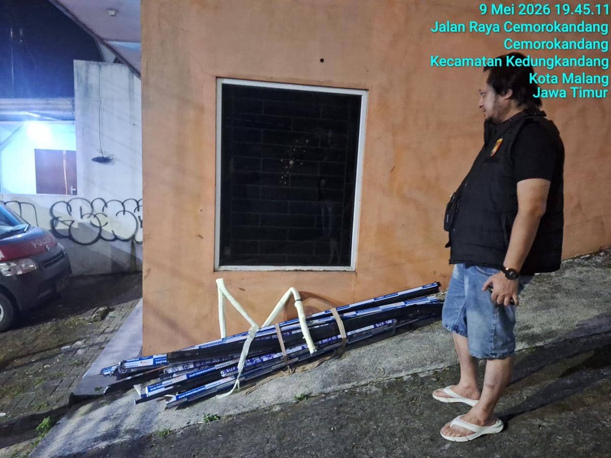 Seorang pria berdiri di depan kantor pemasaran Perumahan Cemara Diamond Townhouse di Malang dengan beberapa batang besi di tanah.