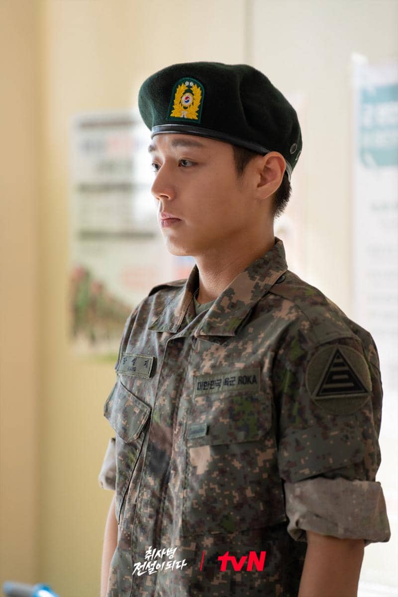 Seorang tentara muda mengenakan seragam militer lengkap dengan baret hijau dalam adegan drama The Legend of Kitchen Soldier.