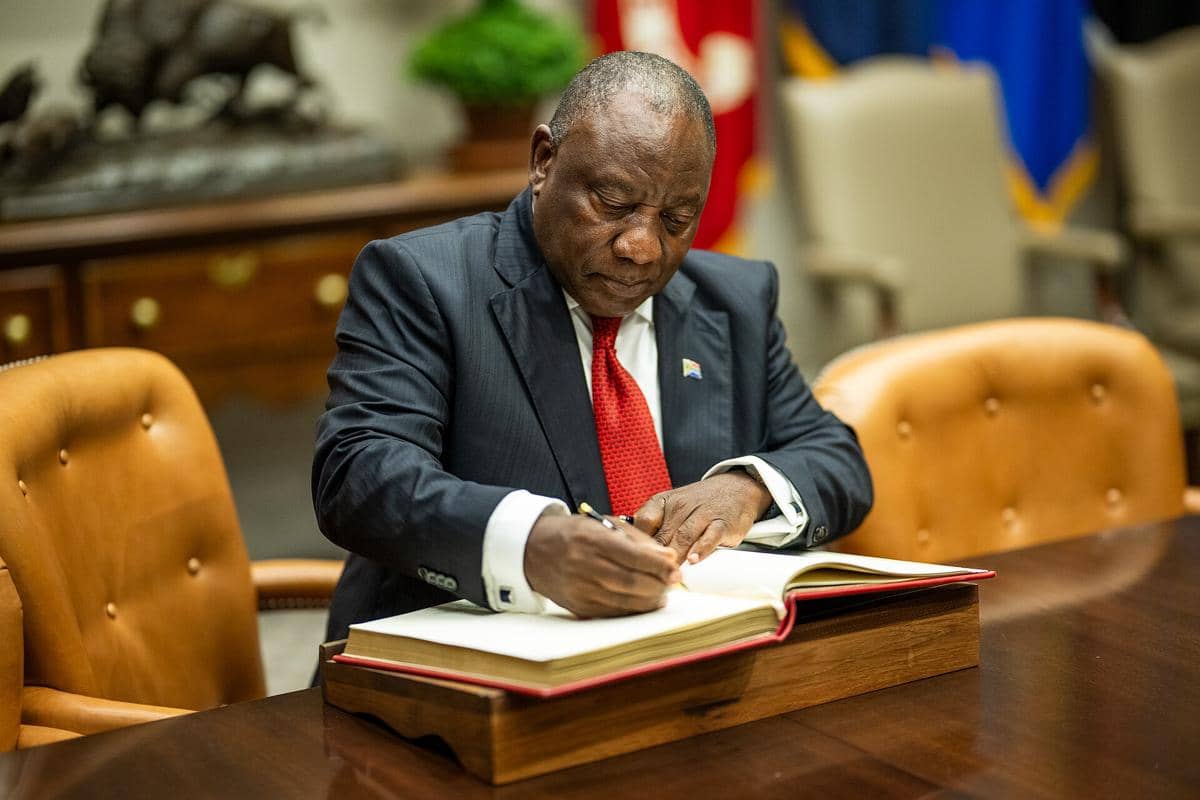Cyril Ramaphosa sedang menandatangani dokumen. 