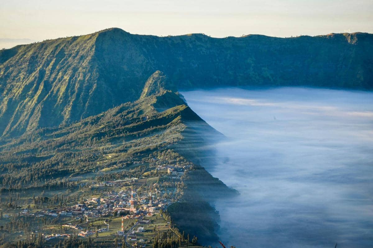 Ilustrasi panorama Gunung Semeru dan lautan awan dari puncak perbukitan.