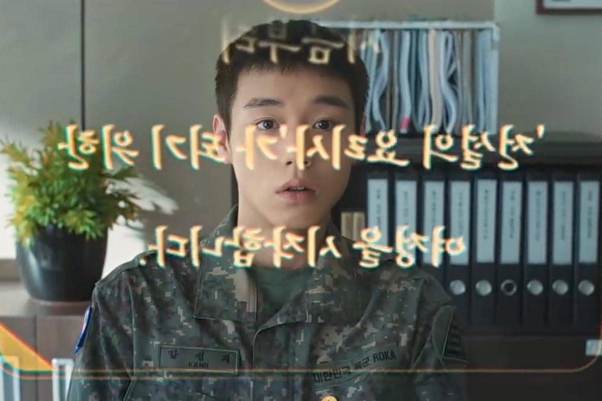 Seorang tentara muda mengenakan seragam militer menatap layar holografik dengan tulisan berbahasa Korea di depannya.