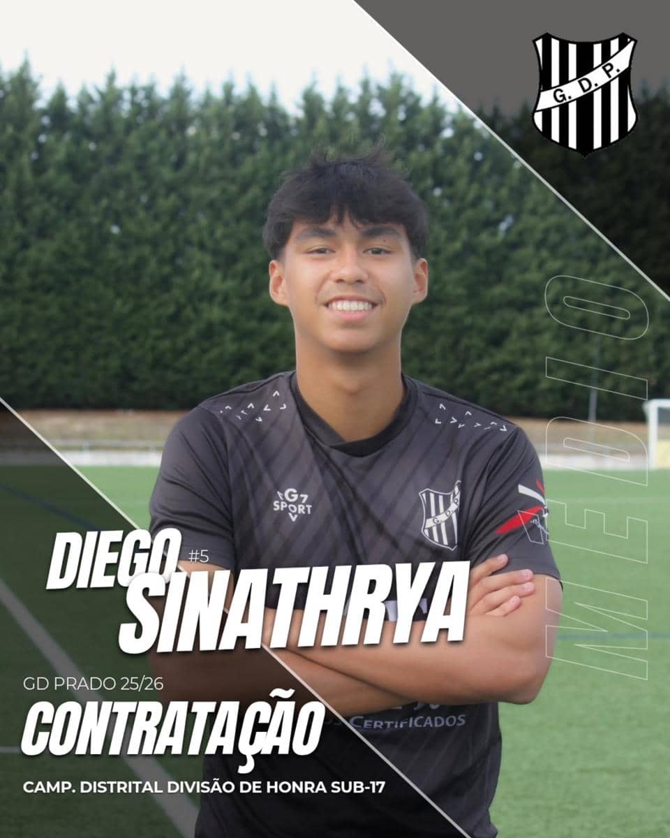 Seorang remaja mengenakan seragam sepak bola hitam dengan logo klub GD Prado, berdiri di lapangan dengan latar pepohonan hijau.