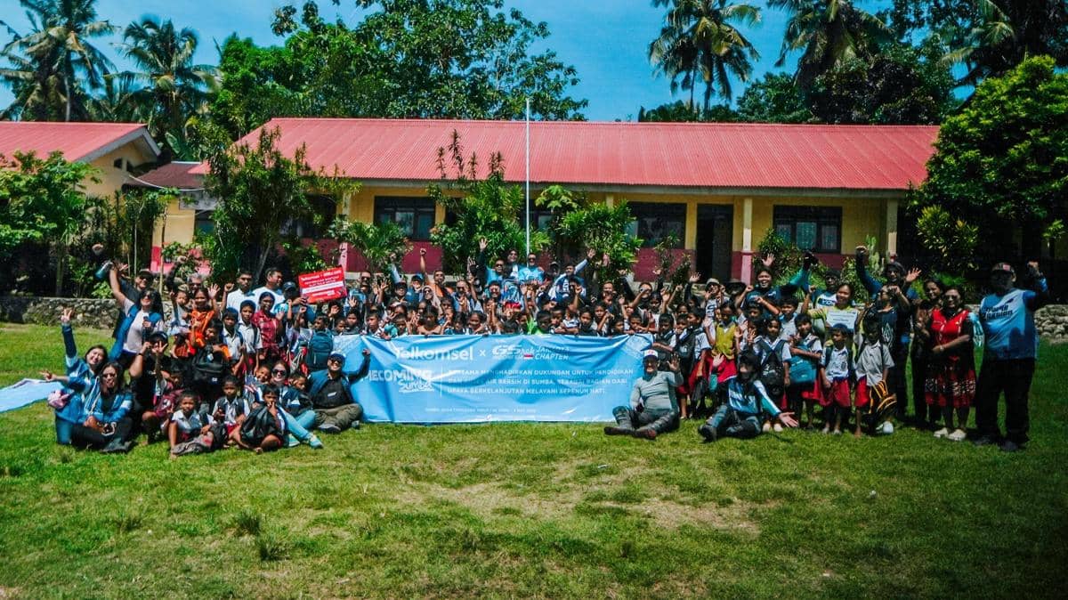 Rombongan peserta Touring GSrek Jakarta berfoto bersama anak-anak di depan bangunan sekolah dengan latar pepohonan hijau.