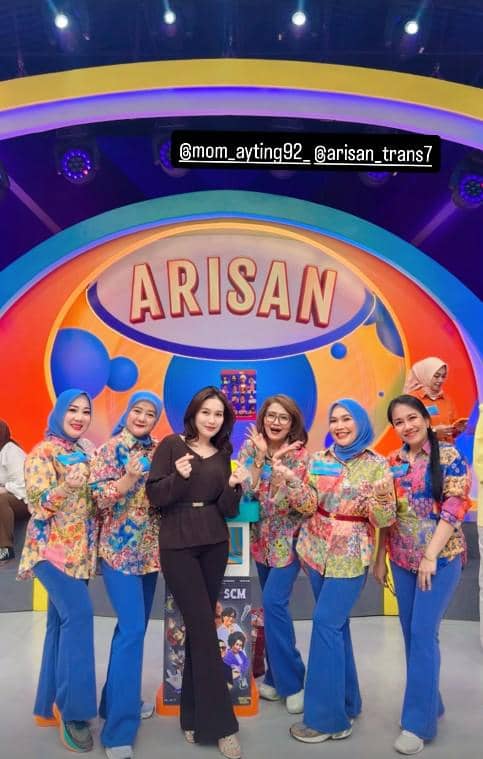 Beberapa wanita berpose ceria di panggung acara kuis Arisan dengan latar warna-warni dan tulisan besar ARISAN di belakang mereka.