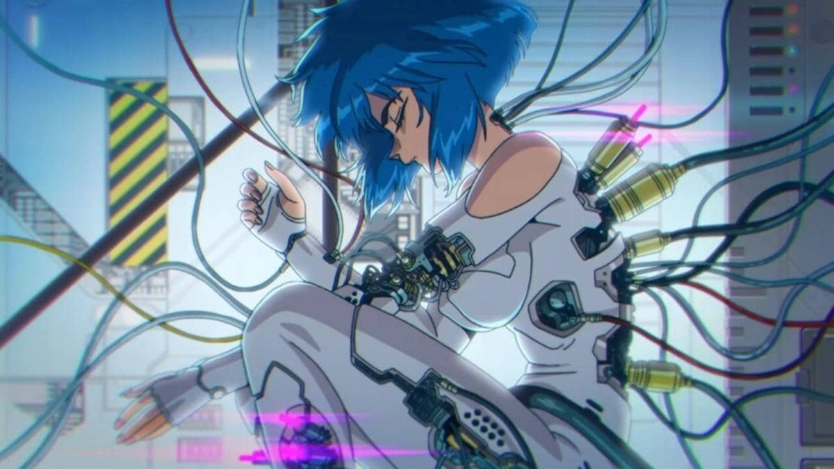 Karakter anime berambut biru dengan pakaian putih terhubung ke berbagai kabel di latar futuristik dari anime Ghost in the Shell (2026).