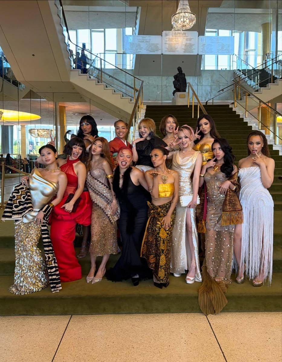 Sekelompok artis berpose di tangga besar dengan gaun glamor dan kain tradisional pada acara Gold House Gold Gala 2026.