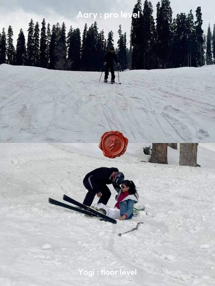 Dua orang bermain ski di lereng bersalju, satu orang meluncur dengan percaya diri sementara yang lain duduk di salju setelah terjatuh.