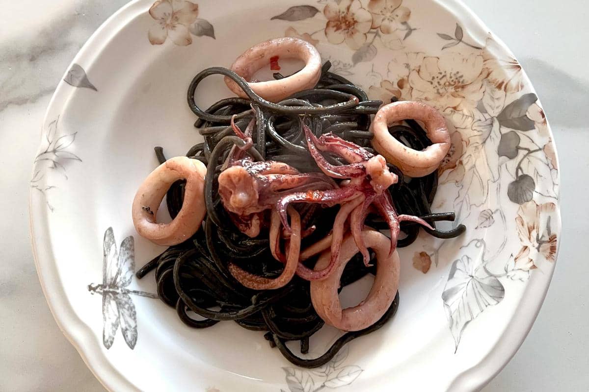 Ilustrasi seporsi nasi cumi hitam khas Madura dengan sambal dan lauk tradisional di meja makan sederhana.