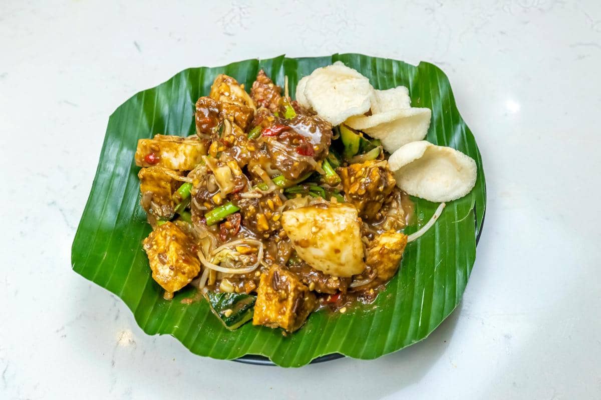  Ilustrasi rujak cingur dan lontong mie khas Surabaya dengan bumbu petis kental di area kaki lima pasar.