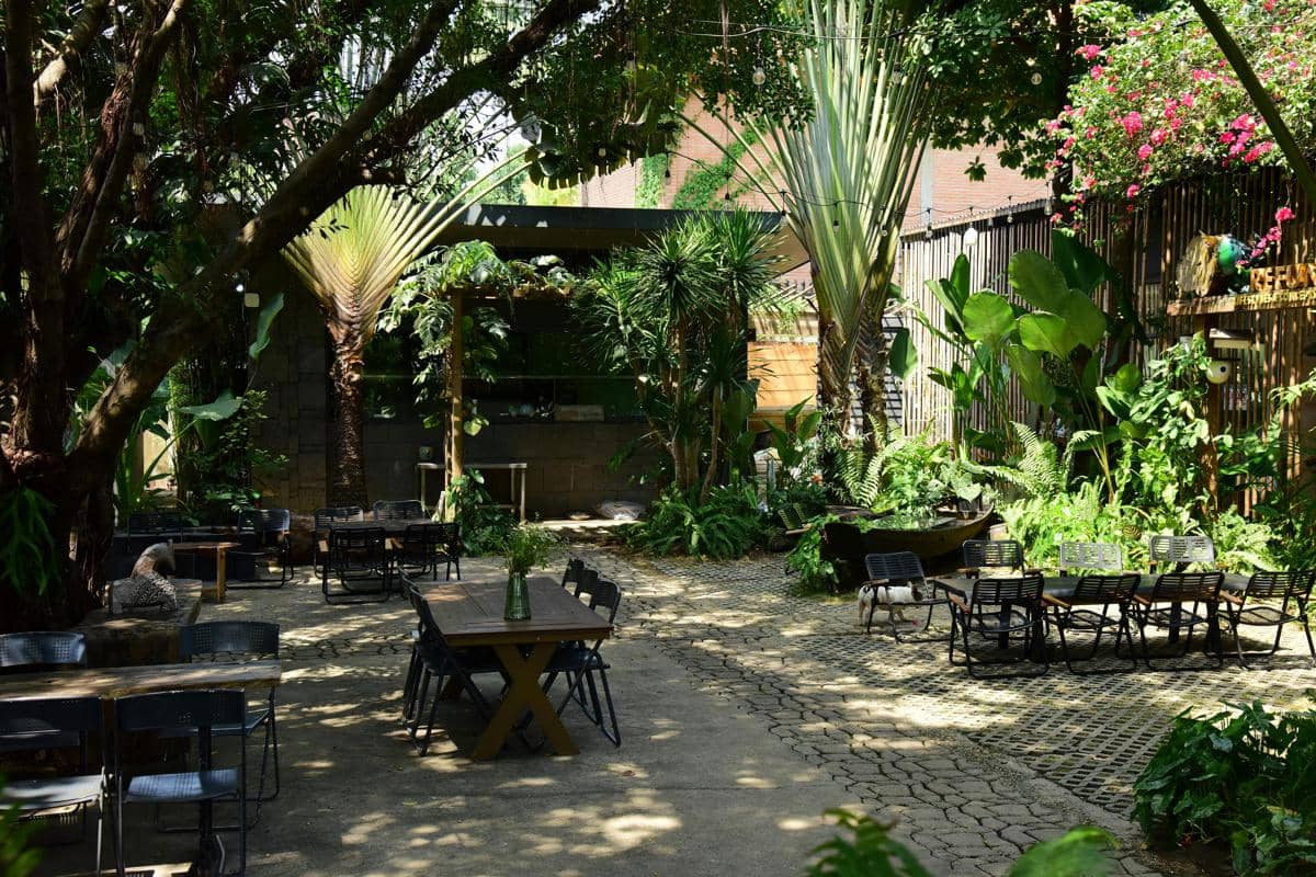 Ilustrasi Kedai Jinawi kedai area outdoor penuh pepohonan yang cocok buat nongkrong sore sampai malam.