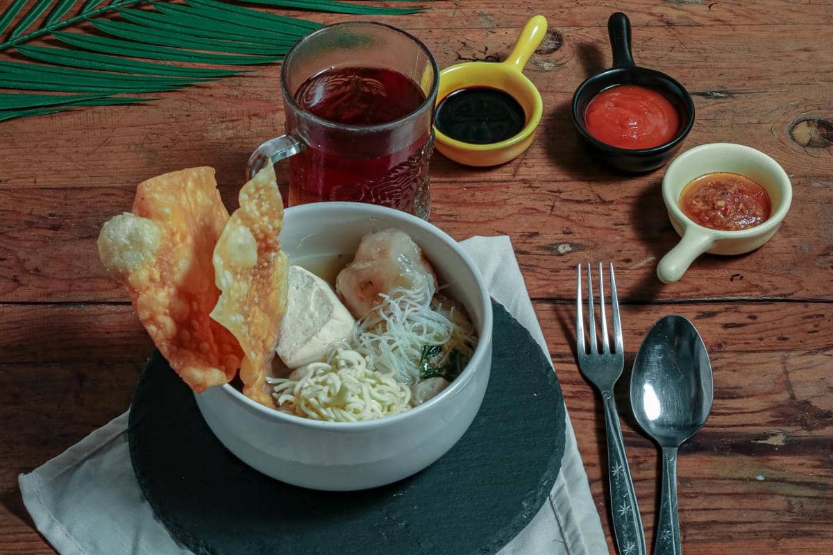  Ilustrasi semangkuk bakwan dan siomay udang dengan kuah kaldu hangat di pusat kuliner Pasar Atom.