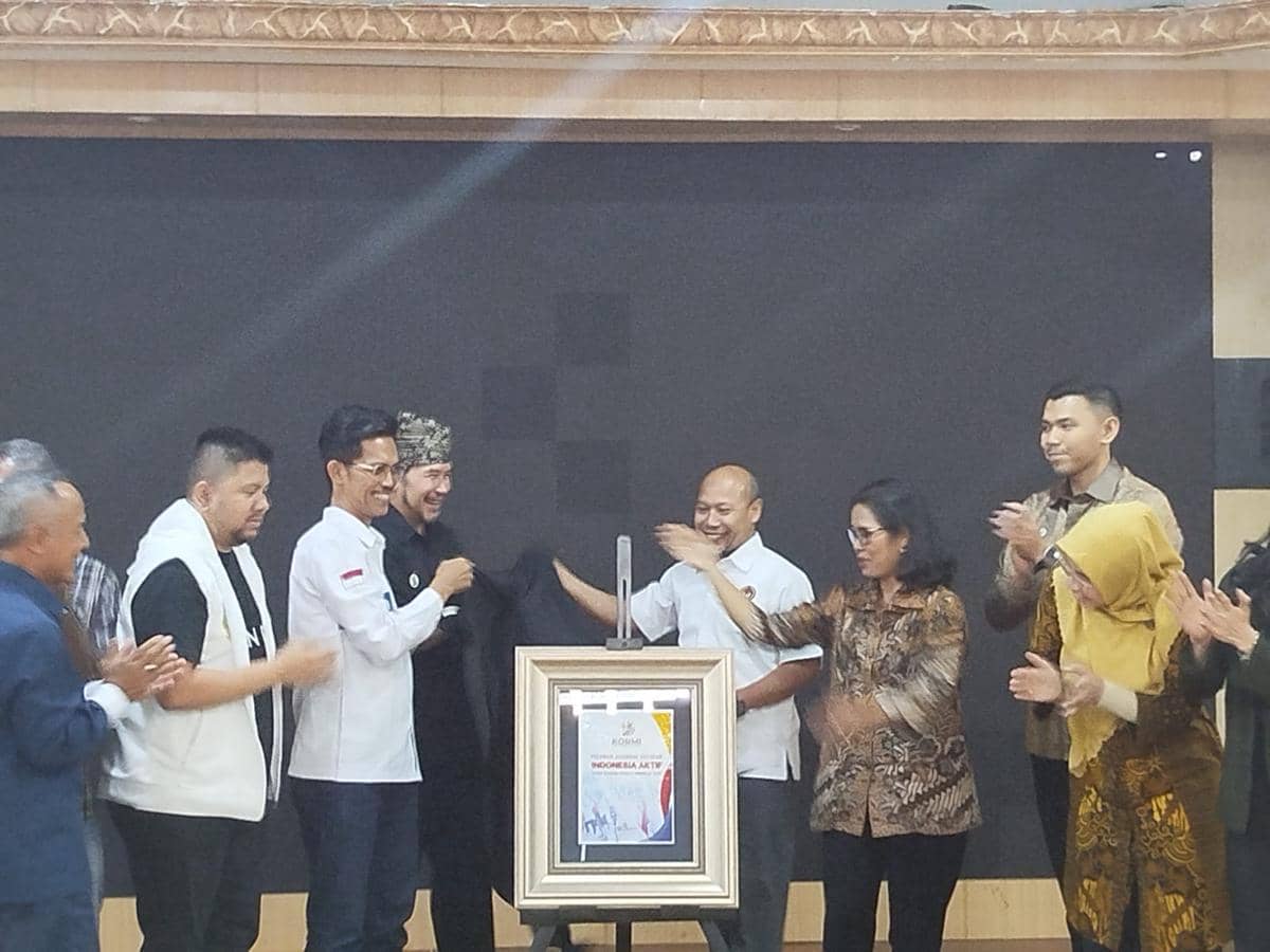 Sejumlah orang bertepuk tangan saat peluncuran Gerakan Indonesia Aktif oleh KORMI di sebuah ruangan dengan latar hitam.