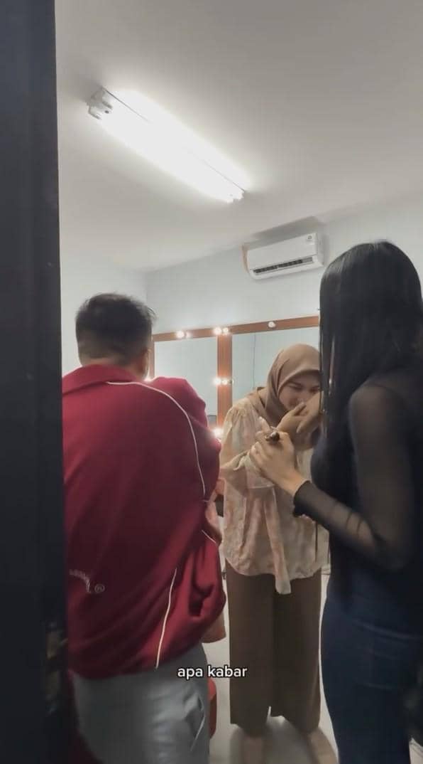 Tiga orang berbincang di ruang rias dengan pencahayaan terang, salah satunya mengenakan hijab dan tampak menunduk sopan.