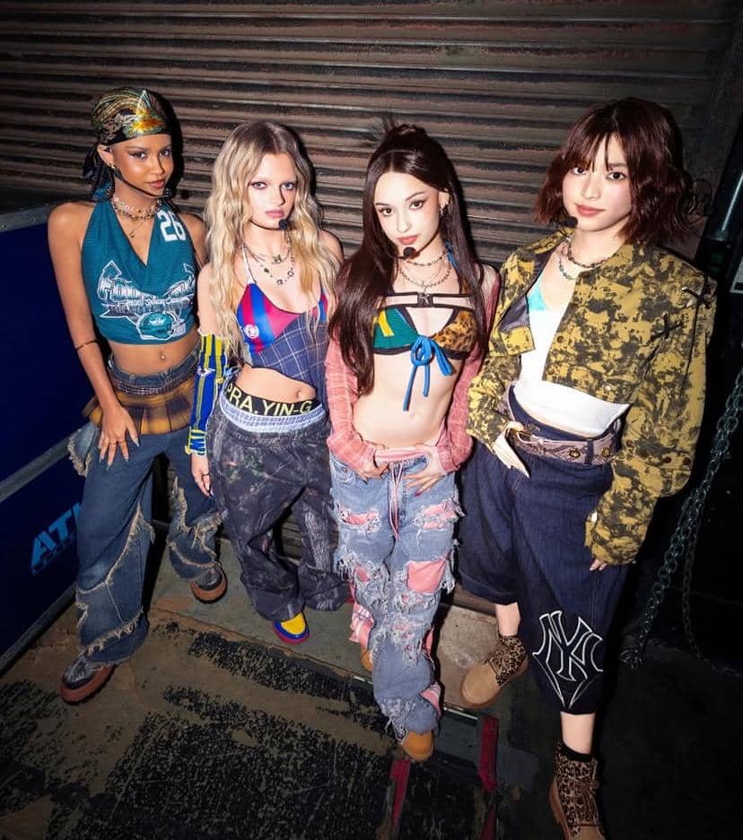 Empat anggota grup SAINT SATINE berpose bersama mengenakan busana bergaya streetwear dengan nuansa warna cerah dan aksesori unik.