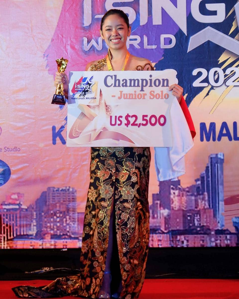 Seorang peserta muda mengenakan kebaya batik memegang trofi dan papan hadiah senilai US$2.500 sebagai juara Junior Solo di ajang iSING World Malaysia.