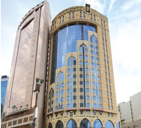 Bangunan tinggi Elaf Al Mashaer Hotel di Makkah dengan fasad kaca biru dan ornamen lengkung bergaya Timur Tengah.