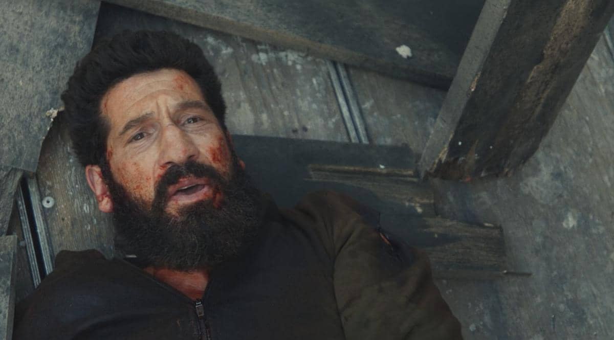 Seorang pria berjanggut dengan wajah berlumuran darah terbaring di lantai kayu dalam cuplikan serial The Punisher: One Last Kill.