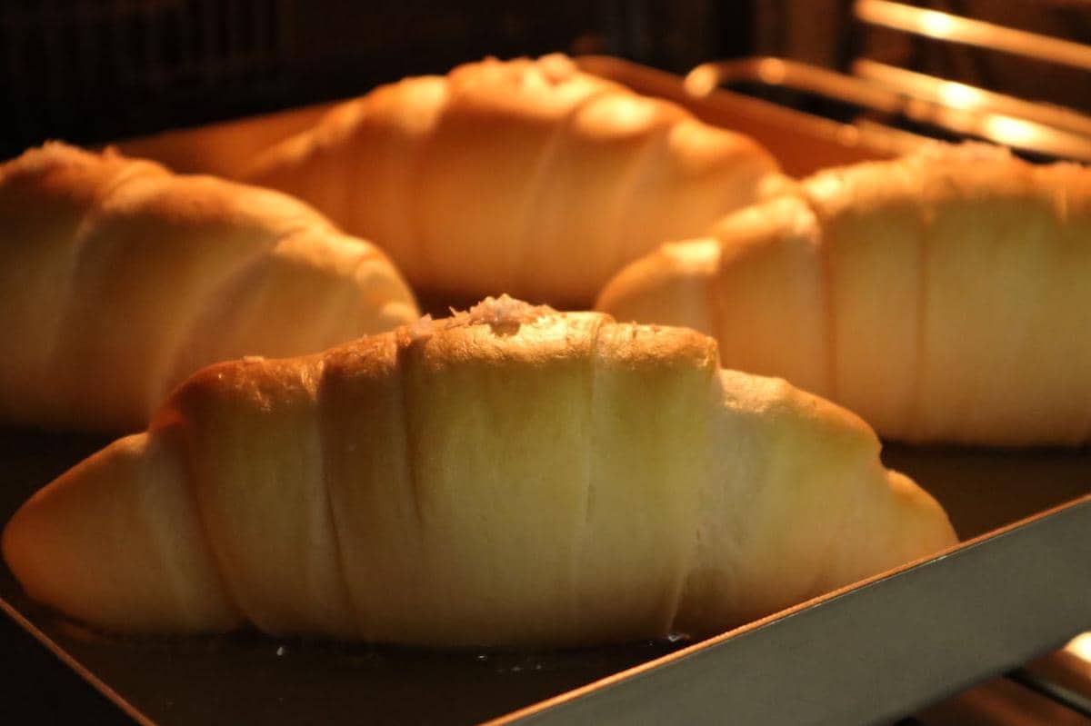 Beberapa roti salt bread berwarna keemasan sedang dipanaskan di dalam microwave dengan loyang logam.
