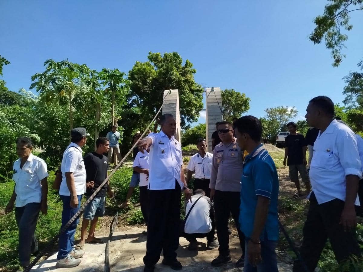 Sejumlah pejabat dan warga meninjau lokasi proyek jembatan gantung yang roboh di kawasan hotel Sumba Barat di bawah langit cerah.