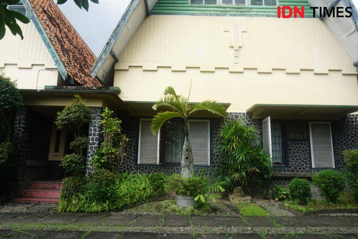 Rumah peninggalan Prof. dr. M. Sardjito di Kelurahan Terban, Yogyakarta dengan dinding batu hitam dan taman hijau di depannya.