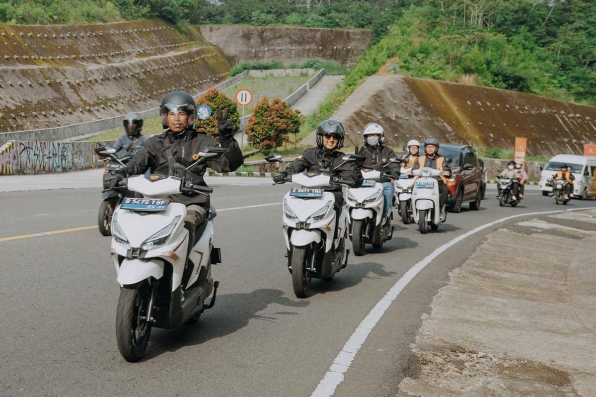 Beberapa pengendara mengendarai skuter listrik Yadea Velax U berwarna putih di jalan berkelok dengan latar perbukitan hijau.