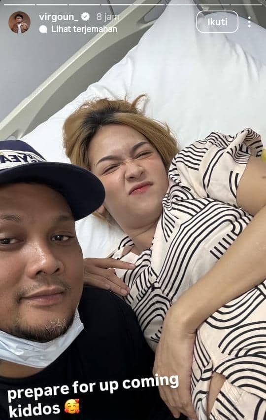 Seorang pria berpose bersama seorang wanita yang berbaring di ranjang rumah sakit dengan ekspresi bahagia menjelang kelahiran anak pertama mereka.