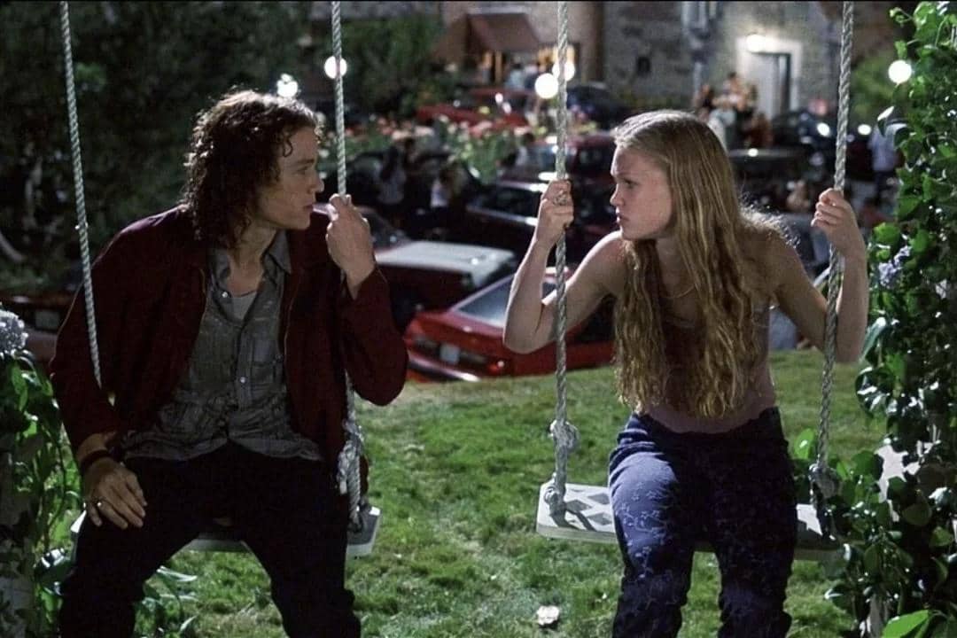 Dua remaja duduk berhadapan di ayunan taman pada malam hari dalam adegan film 10 Things I Hate About You.