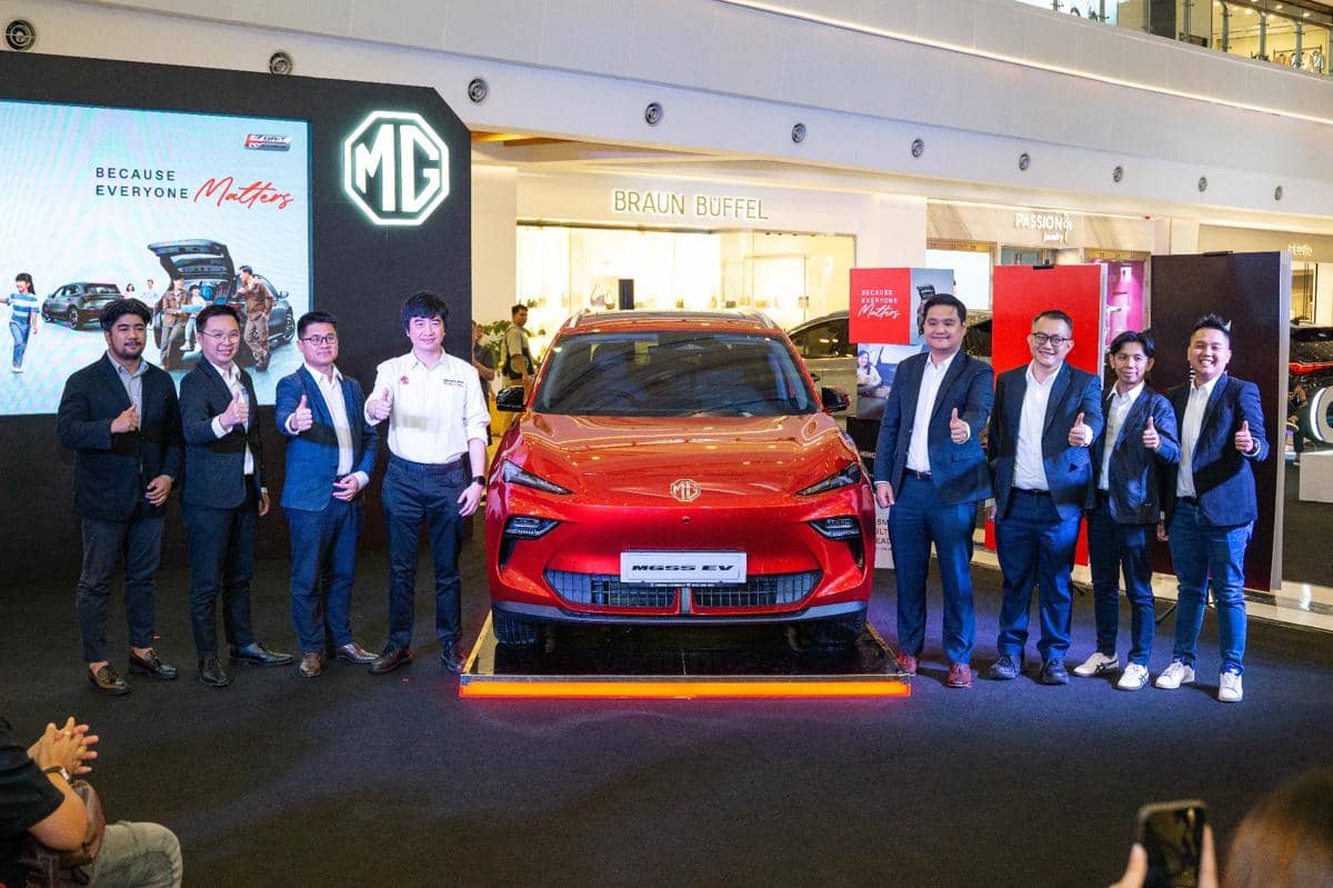 Peluncuran mobil listrik MG4 EV berwarna merah dengan sejumlah eksekutif MG berpose bersama di sebuah pusat perbelanjaan.