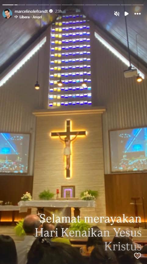 Umat menghadiri ibadah Hari Kenaikan Yesus Kristus di gereja dengan salib besar bercahaya dan jendela kaca berwarna di latar belakang.