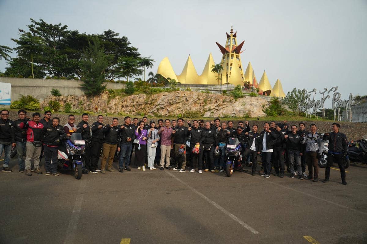 Rombongan pengendara motor berpose bersama di depan Menara Siger Lampung dengan latar bangunan berwarna emas yang ikonik.