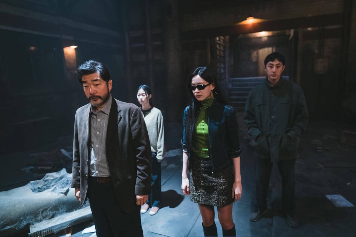 Empat karakter berdiri di ruangan gelap dengan pencahayaan redup dalam adegan drama Korea The WONDERfools di Netflix.