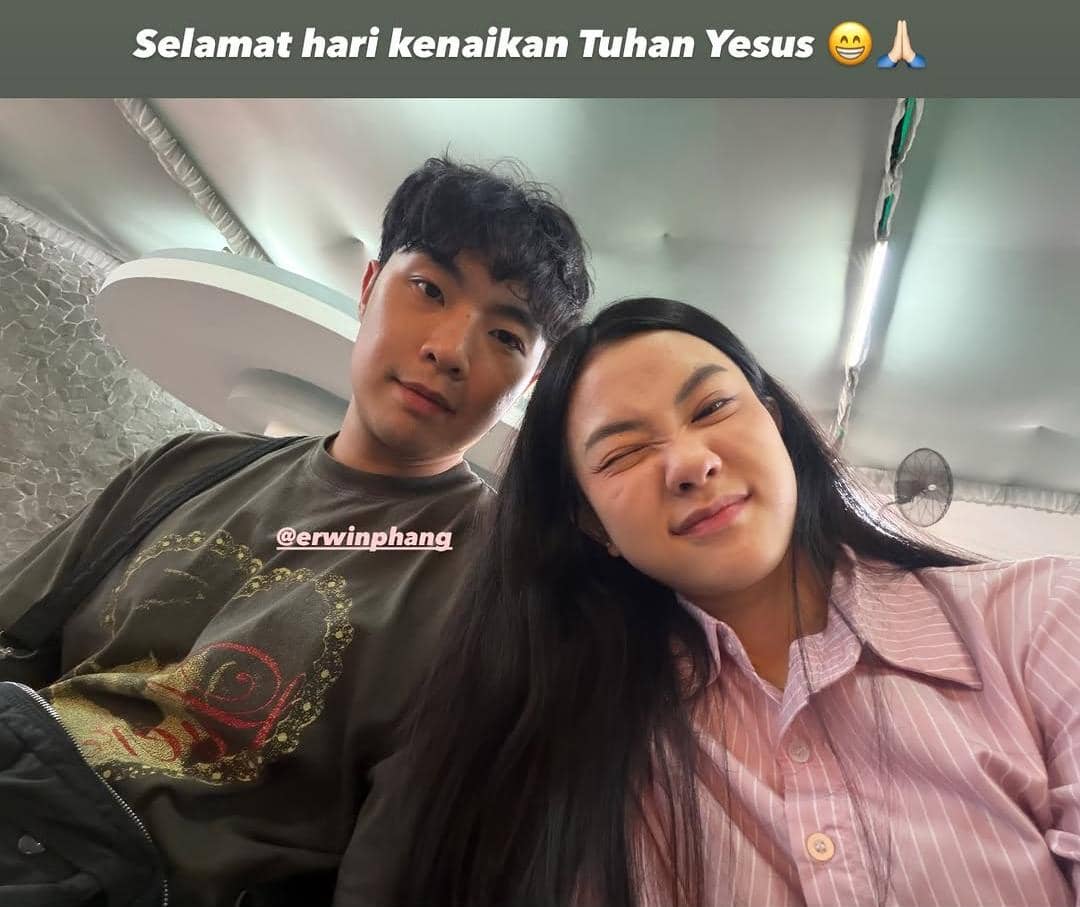 Dua orang berpose bersama sambil tersenyum di dalam ruangan dengan ucapan Selamat Hari Kenaikan Tuhan Yesus di bagian atas foto.