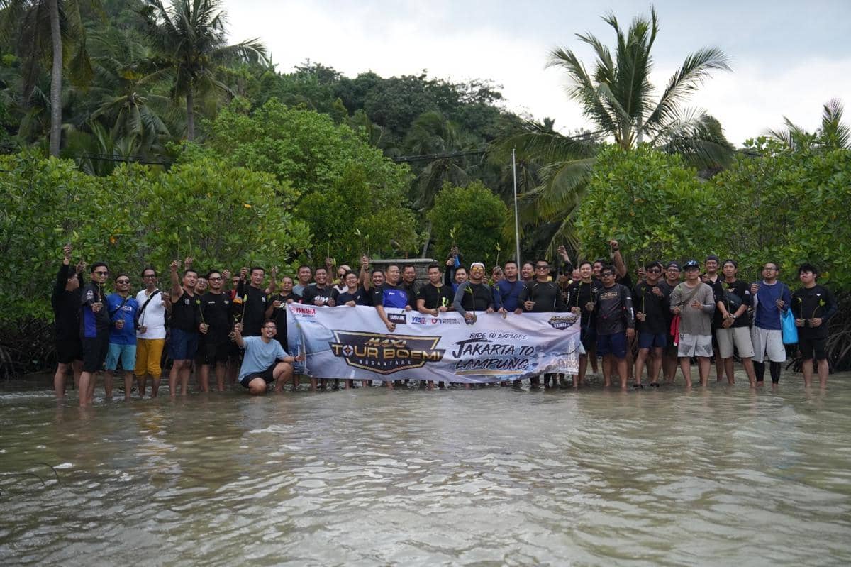 Sekelompok peserta kegiatan JMC berdiri di perairan dangkal sambil memegang bibit mangrove dan membentangkan spanduk bertuliskan Jakarta to Lampung.