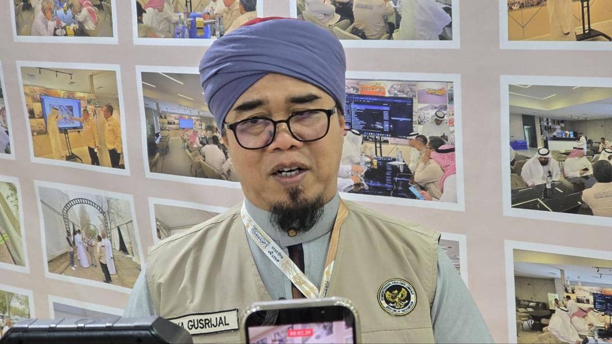 Seorang petugas berpakaian resmi dengan sorban ungu dan rompi berlogo pemerintah memberikan wawancara di Kantor Daker Makkah.