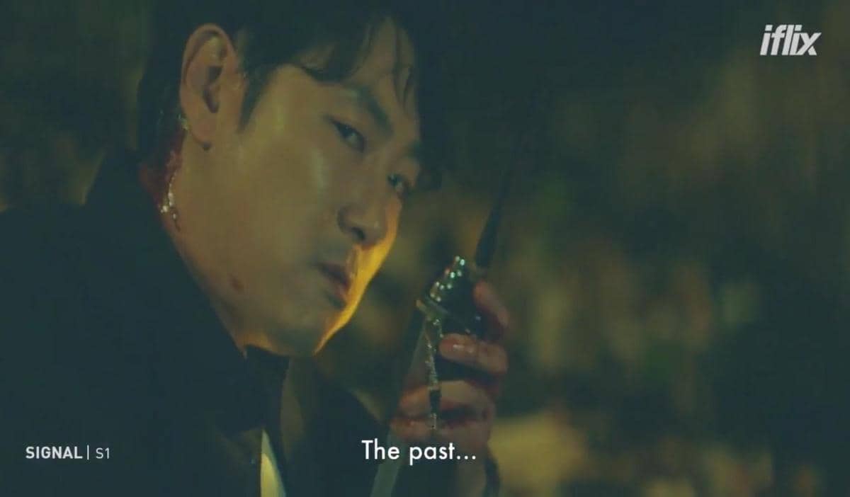 Seorang pria dengan luka di leher memegang walkie-talkie di malam hari dalam cuplikan drama Signal dari iflix Malaysia.